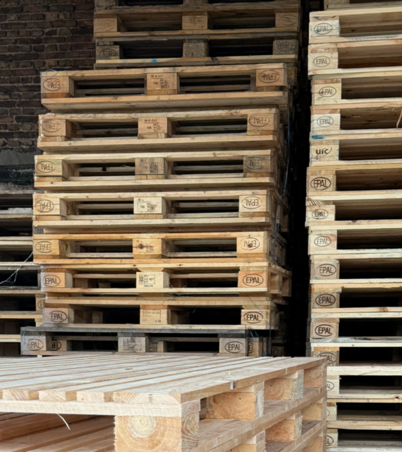 Magazyn z wysokimi stosami certyfikowanych palet EPAL i palet przemysłowych gotowych do wysyłki.