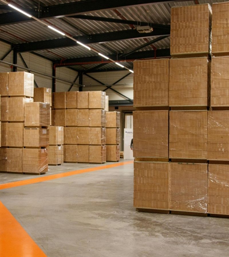 Duży plac składowy z tysiącami palet drewnianych w Trzebini, widok z góry na magazyn zewnętrzny i pracujący wózek widłowy.